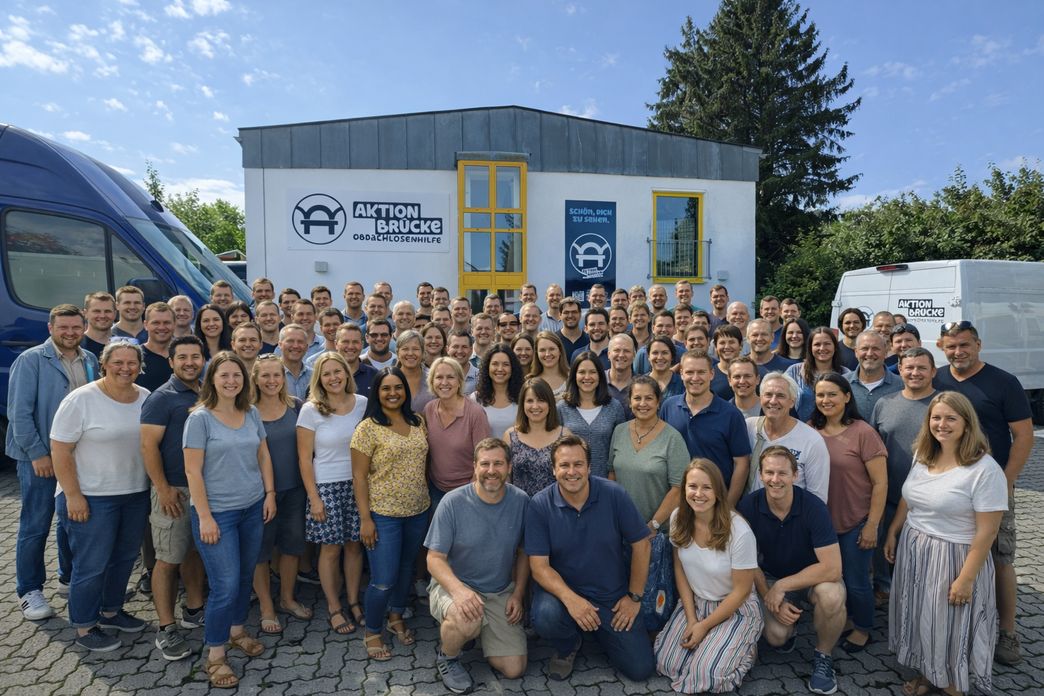 viele Menschen als Team von der Aktion Brücke stehen vor einem kleinen Haus